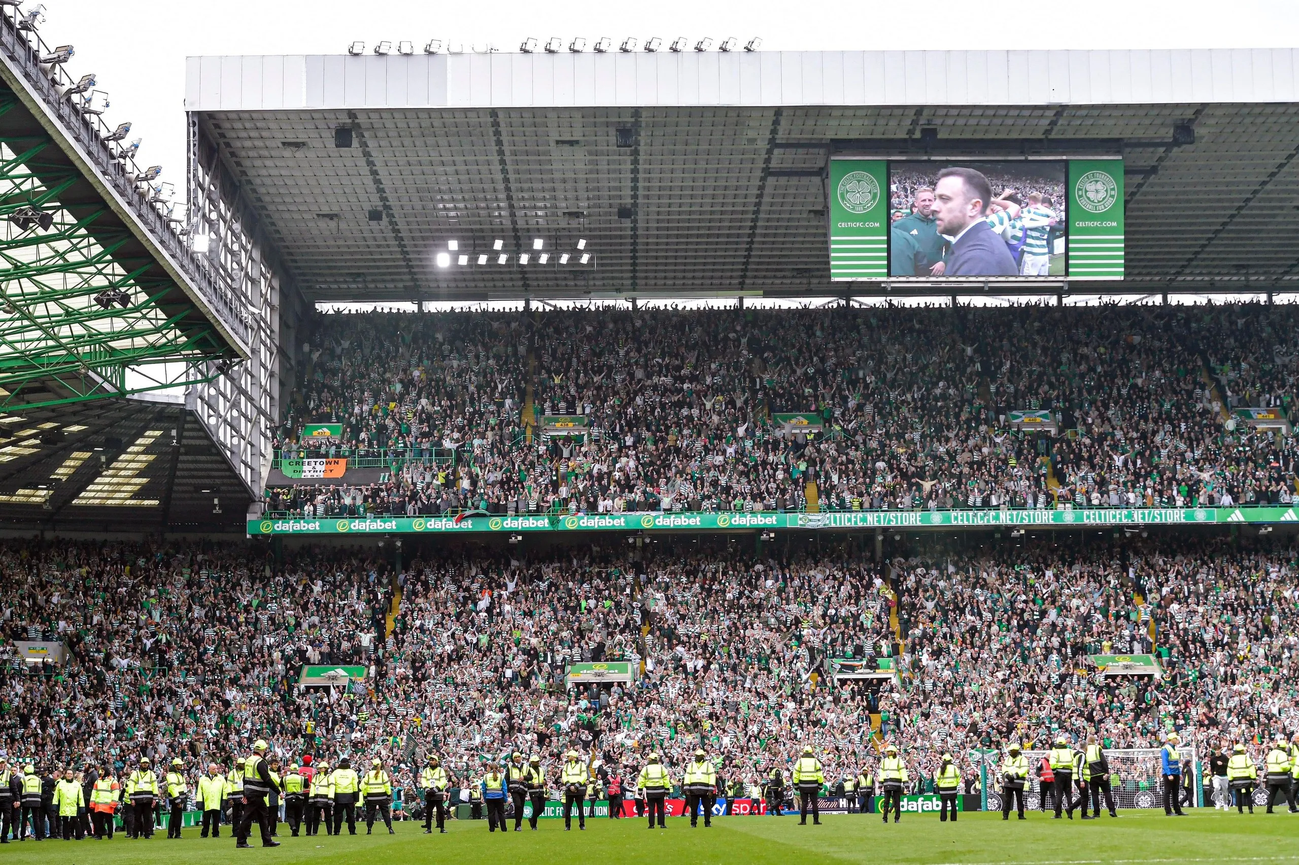 A line of stewards keeps fans apart after the pitch invasion at Celtic Park.