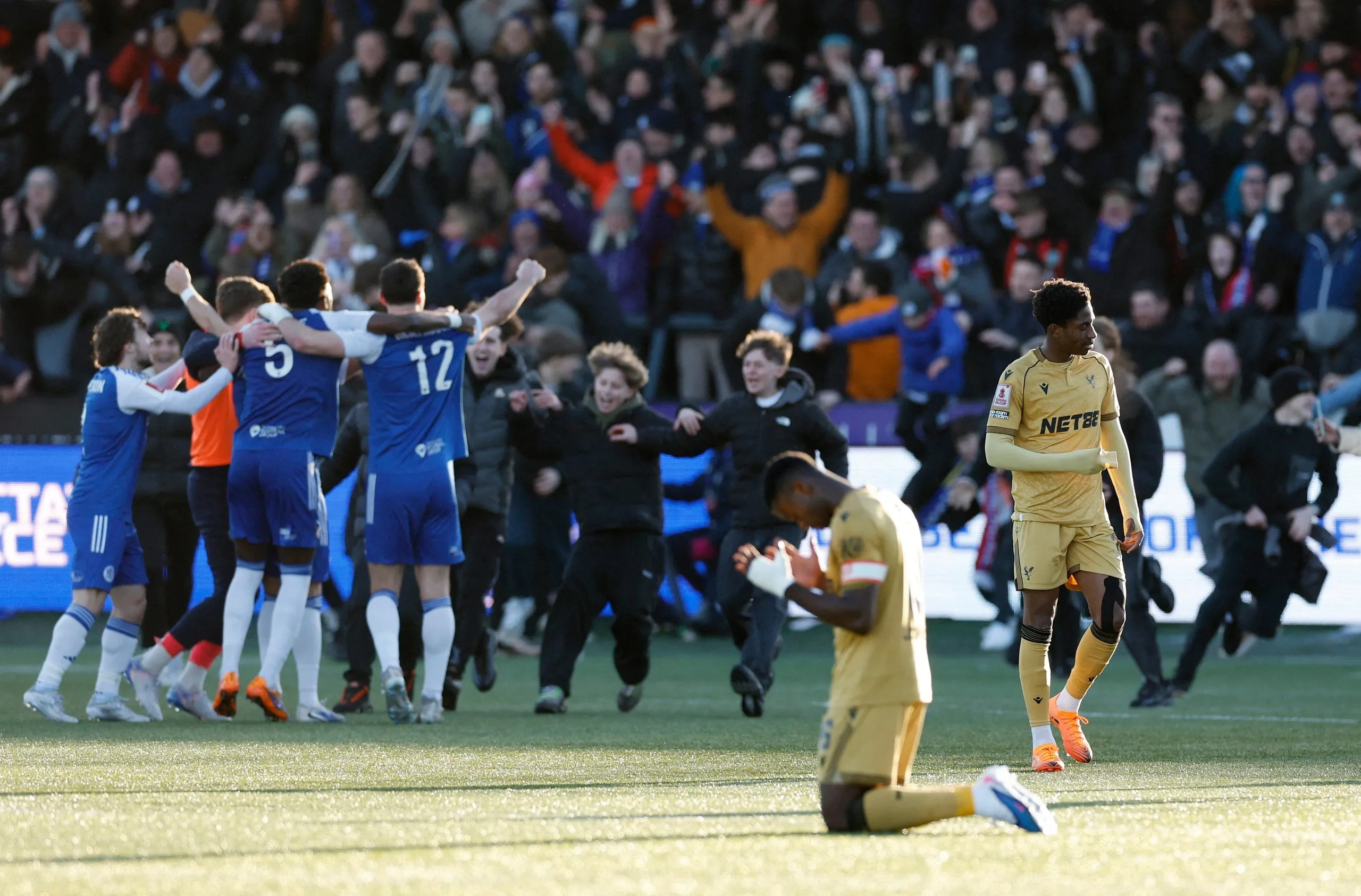 Marc Guéhi is on his knees as Macclesfield celebrate their victory against Crystal Palace. 