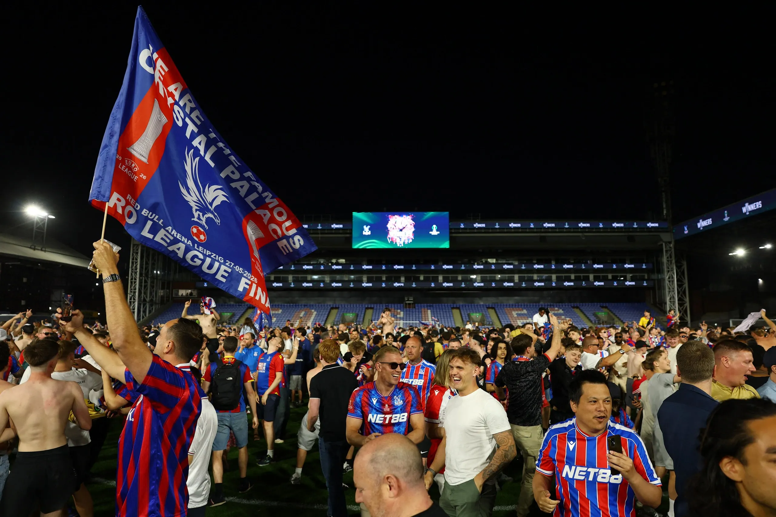 Crystal Palace fans celebrate on the Selhurst pitch after winning the UEFA Conference League final.