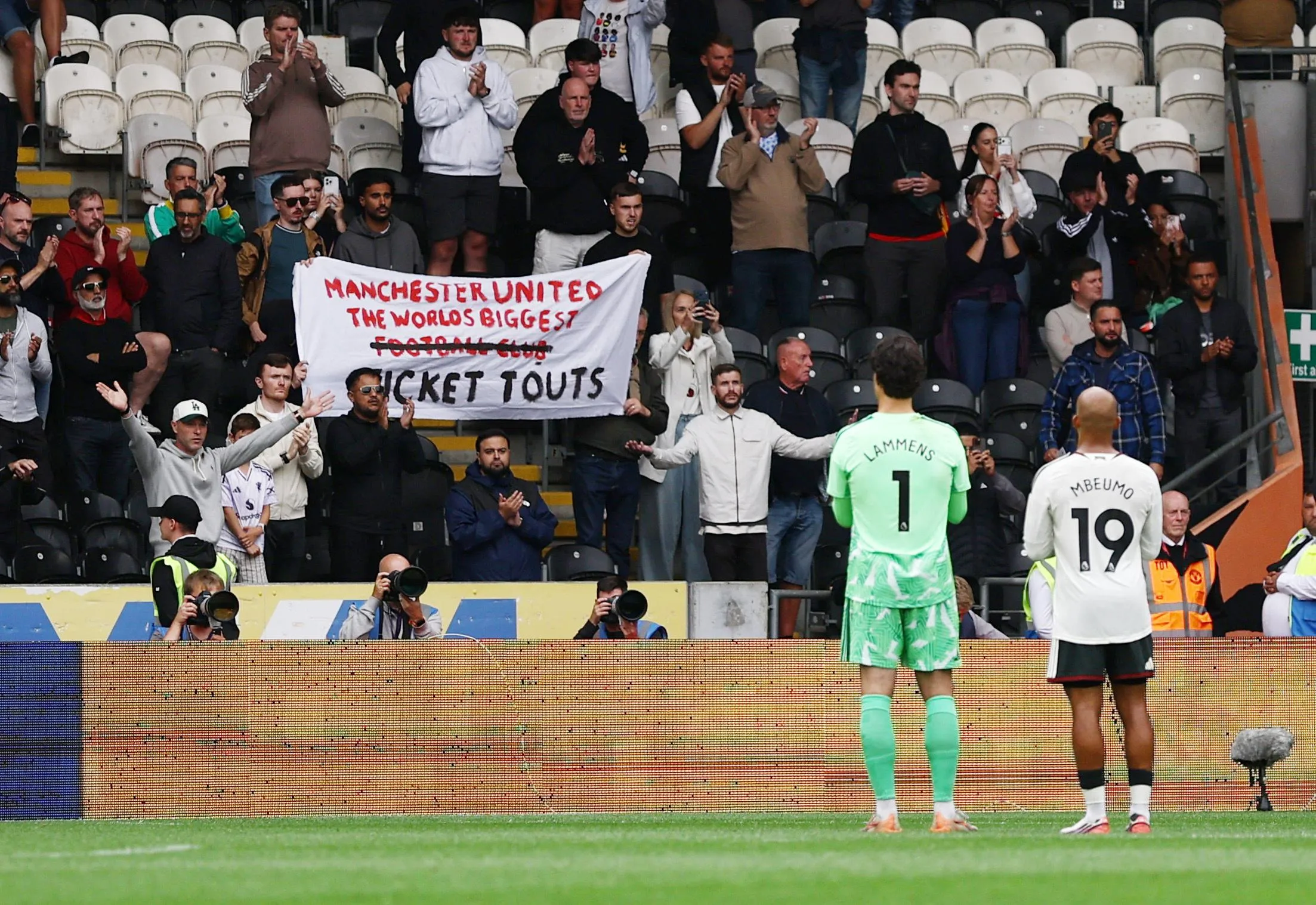 Supporters with a banner that reads ‘Manchester United: The World’s Biggest Football Club Ticket Touts’ as Senne Lammens and Bryan Mbeumo applaud fans after the Premier League match between Hull and Manchester United