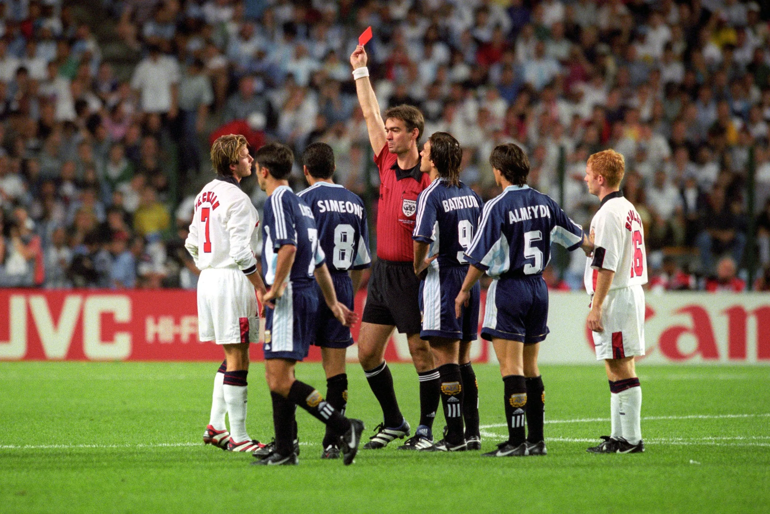 Referee Kim Milton Nielsen shows the red card to David Beckham while being surrounded by players