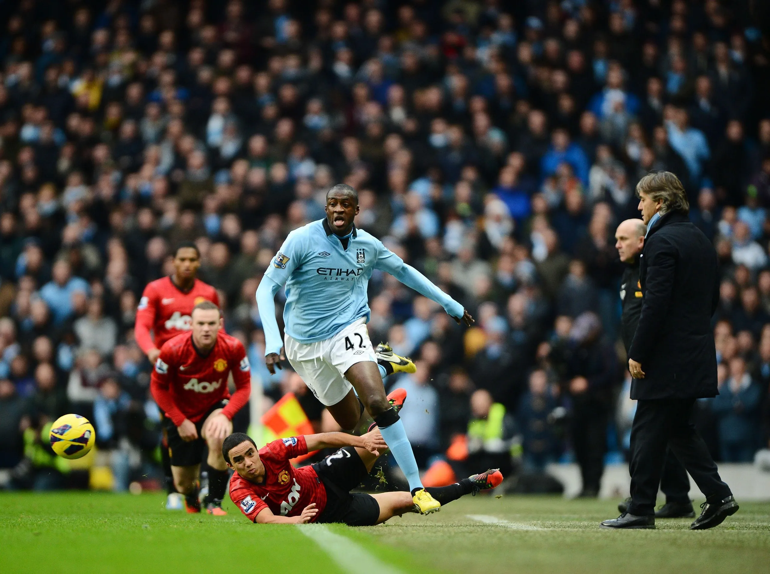 Roberto Mancini looks on as Yaya Touré is tackled by Rafael da Silva of Manchester United