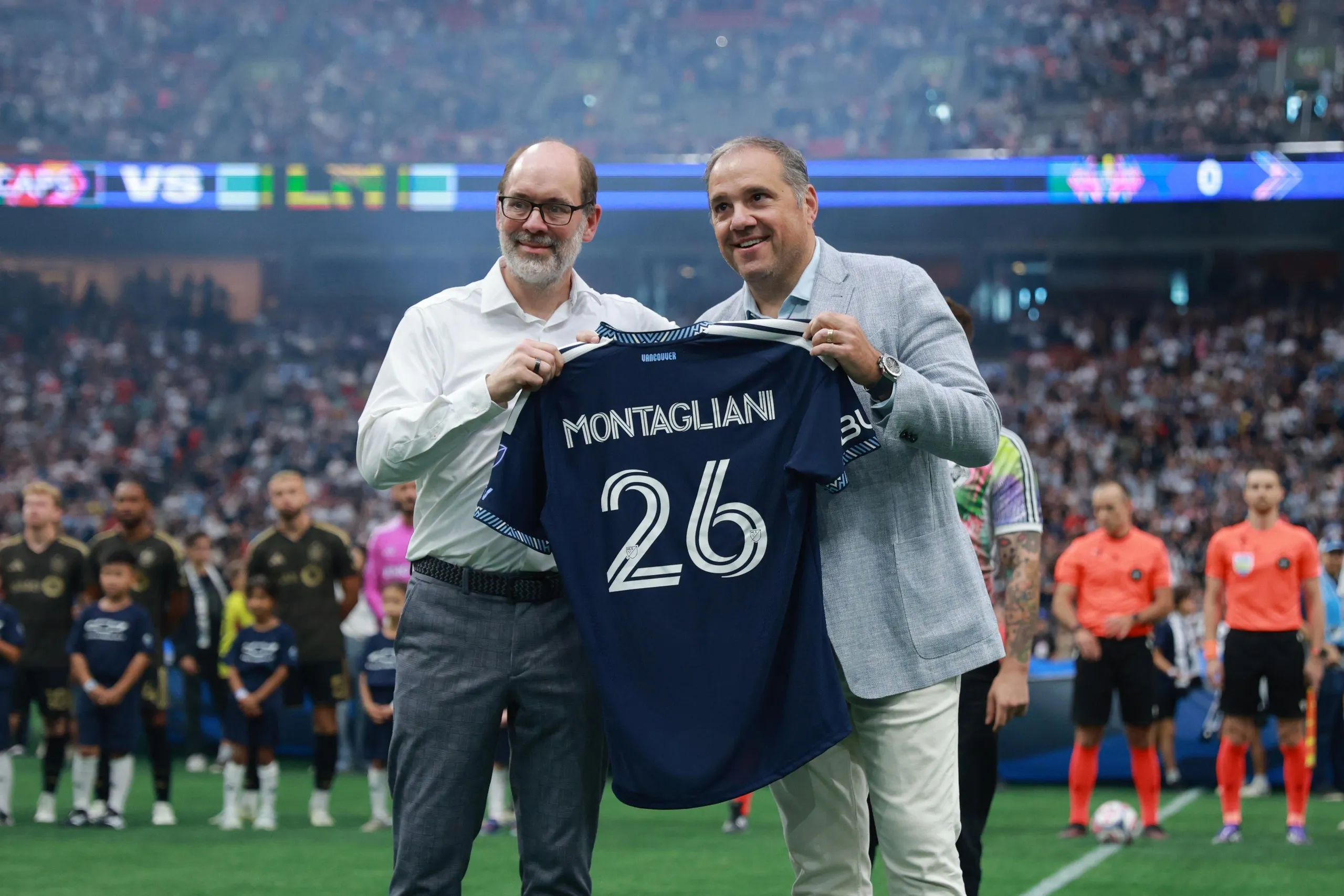 Victor Montagliani (right) receives a jersey from Axel Schuster, CEO and sporting director of Vancouver Whitecaps, prior to the MLS match between Vancouver Whitecaps FC and Los Angeles 
