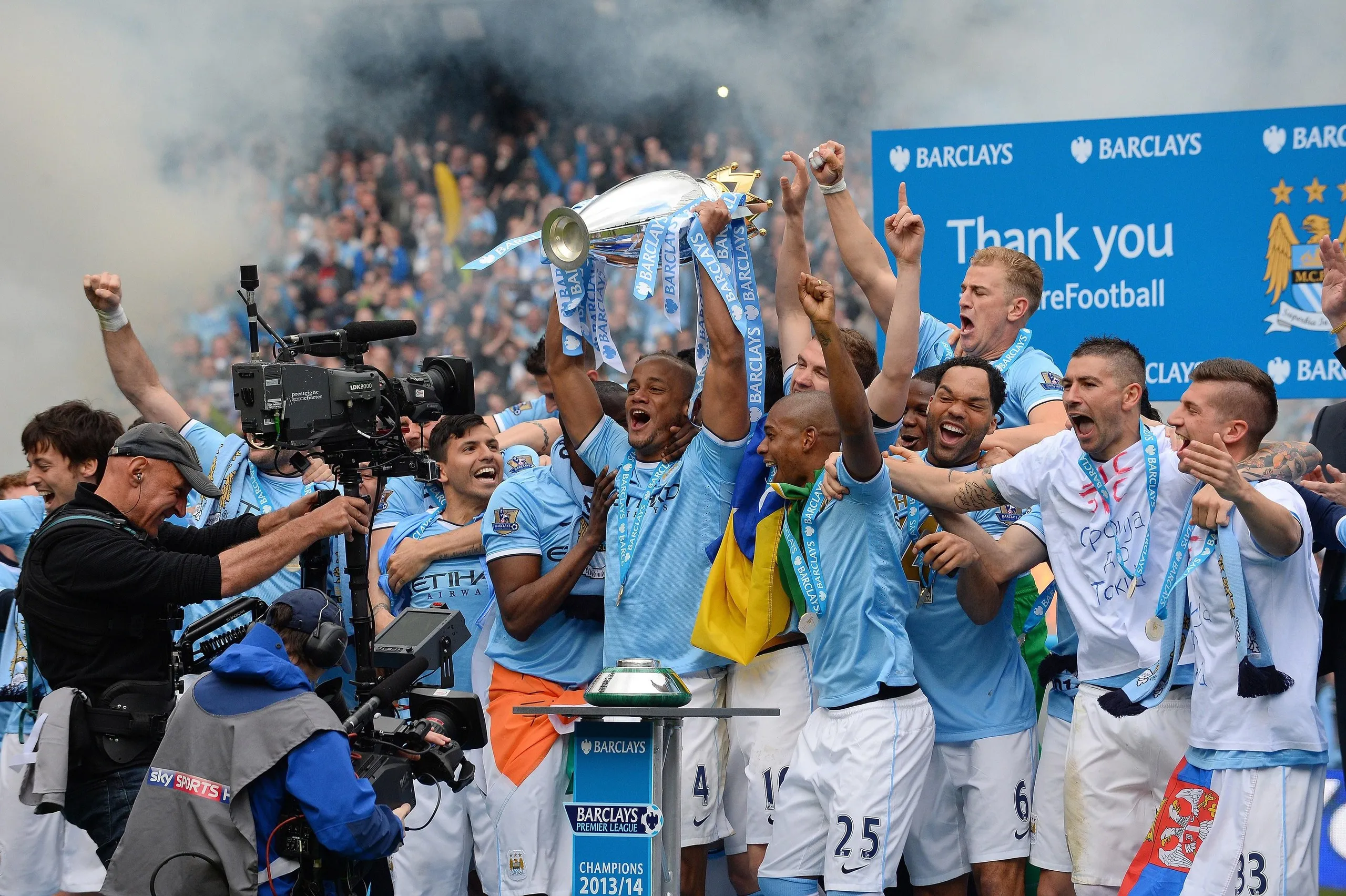 Manchester City’s Vincent Kompany lifts the Premiership trophy in the air surrounded by his teammates