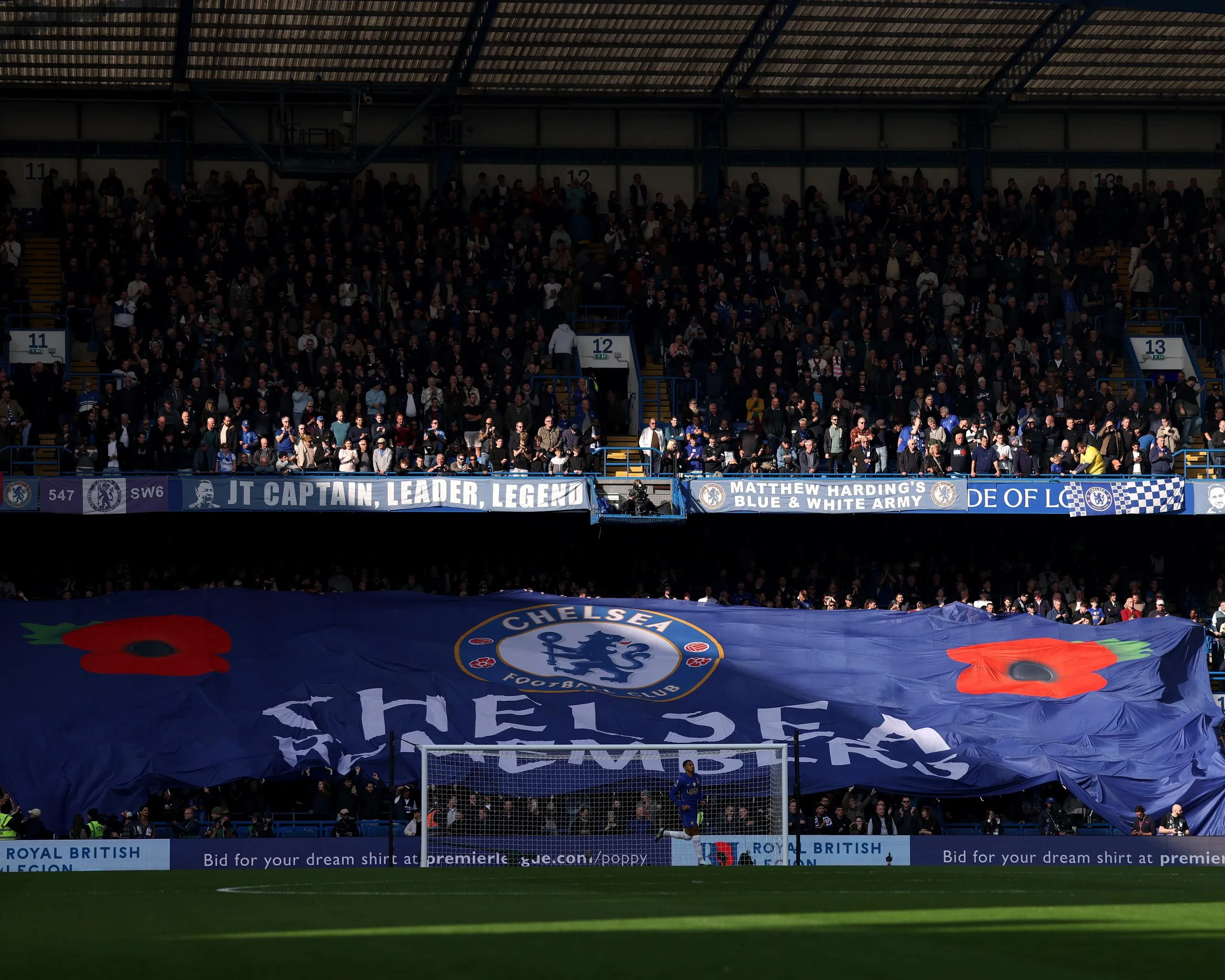 Chelsea fans display a large flag that reads "Chelsea Remembers" with the remembrance poppy to honour military service members that have died in war.