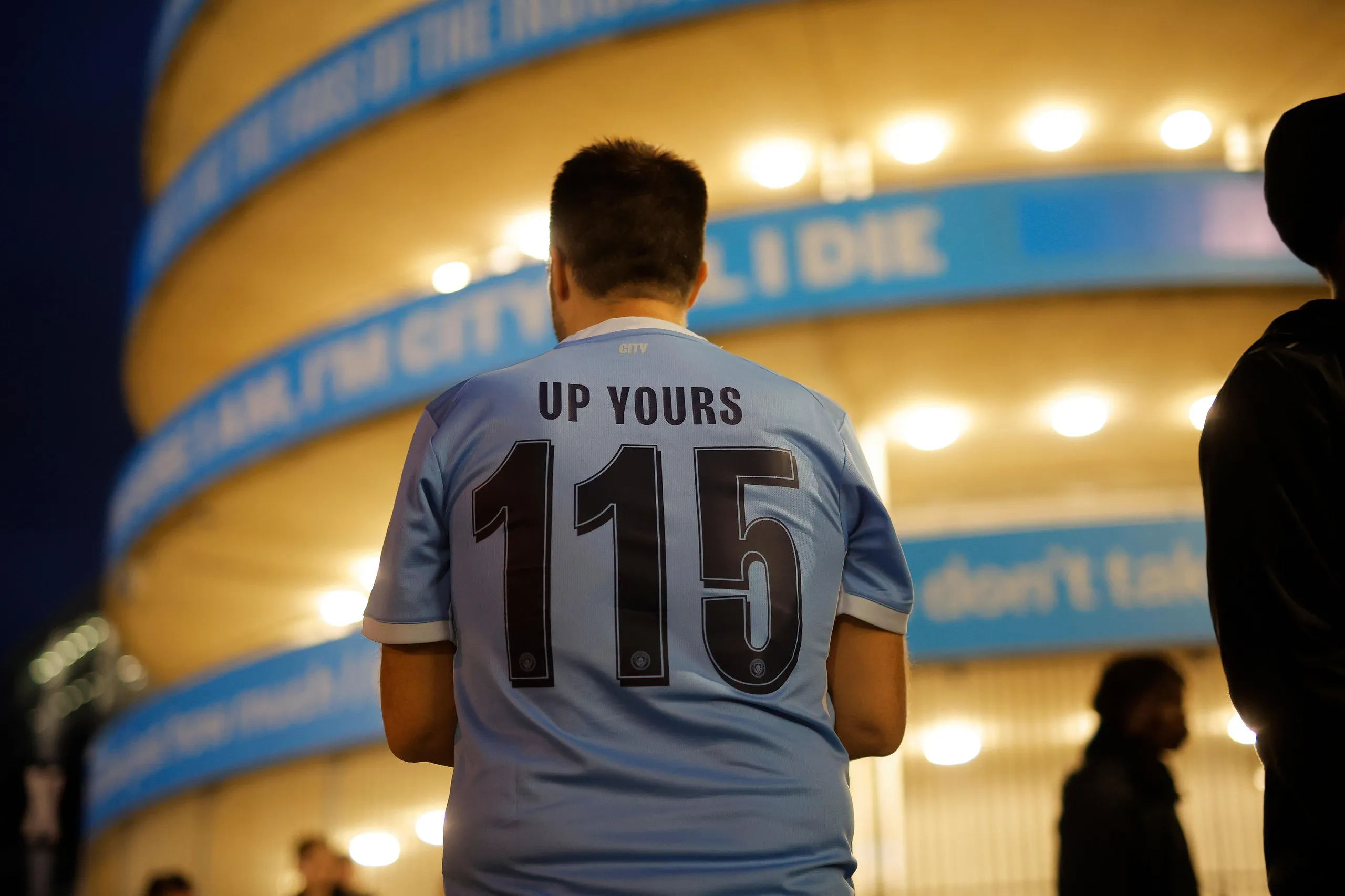 Manchester City fan wearing a '115, up yours' t-shirt at the stadium
