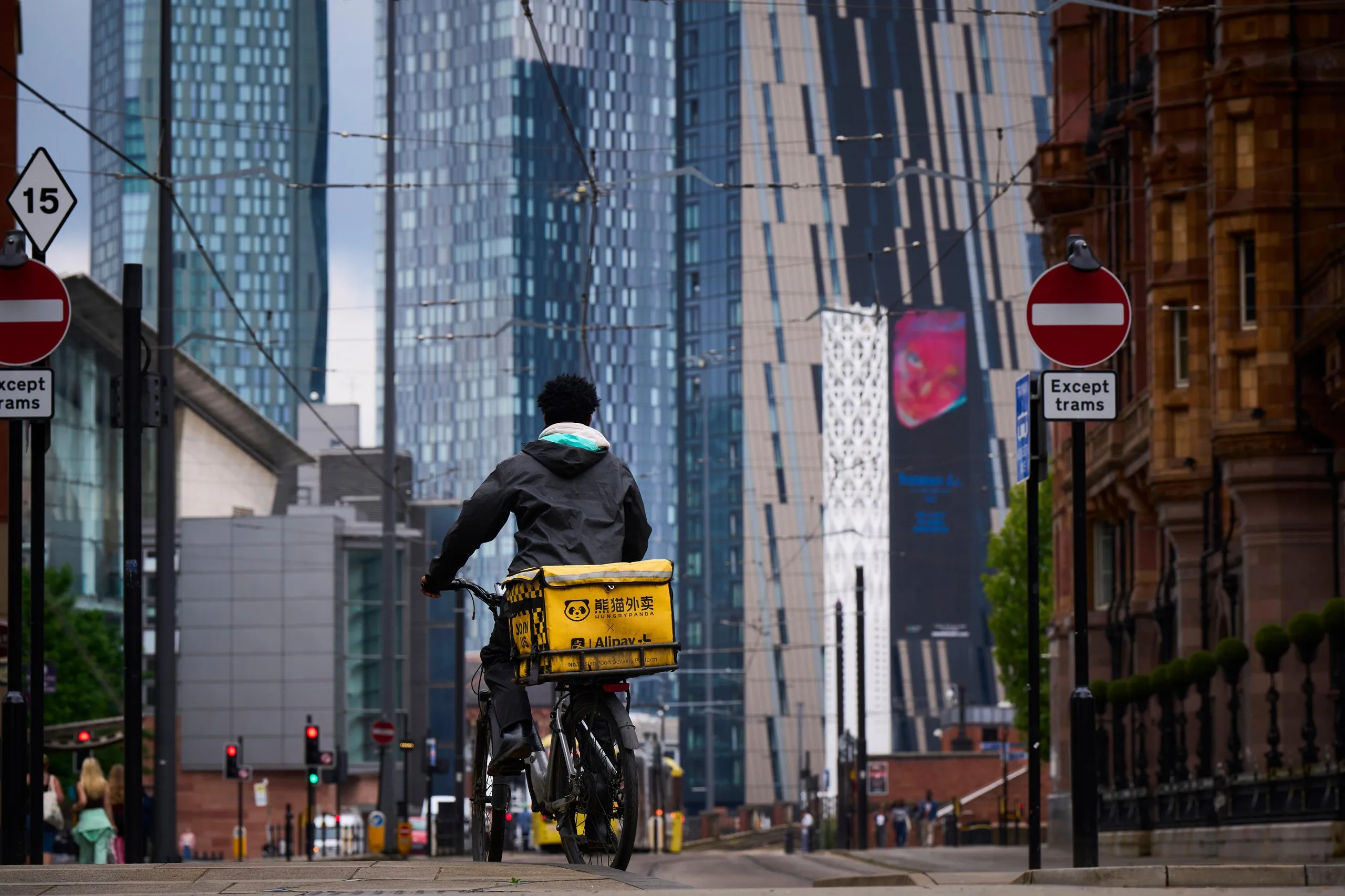 Skyscrapers in St Peter’s Square, Manchester, and a cycle courier with a yellow box on the back